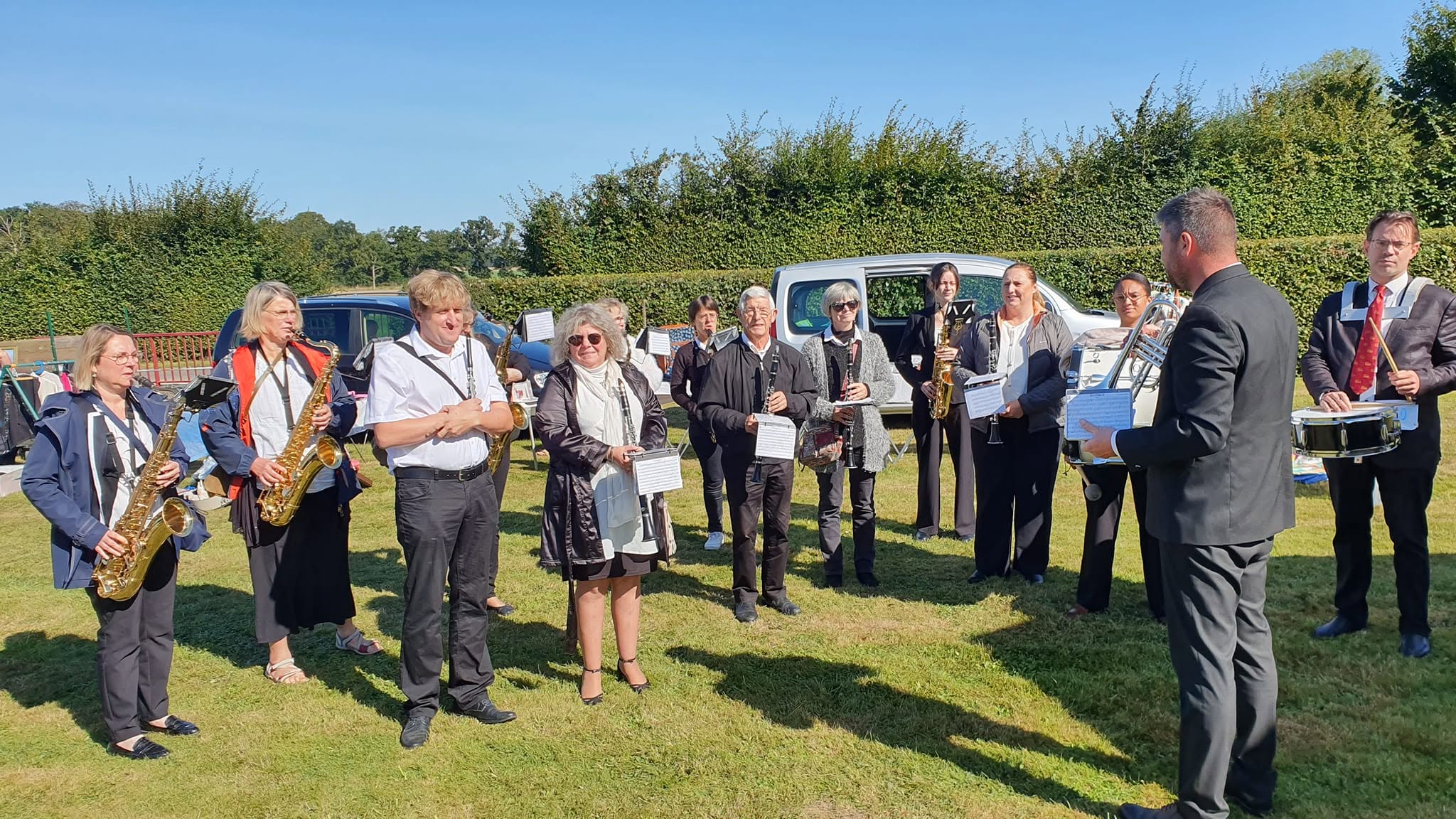 L'orchestre réuni sur l'herbe en plein soleil, le chef face aux musiciens