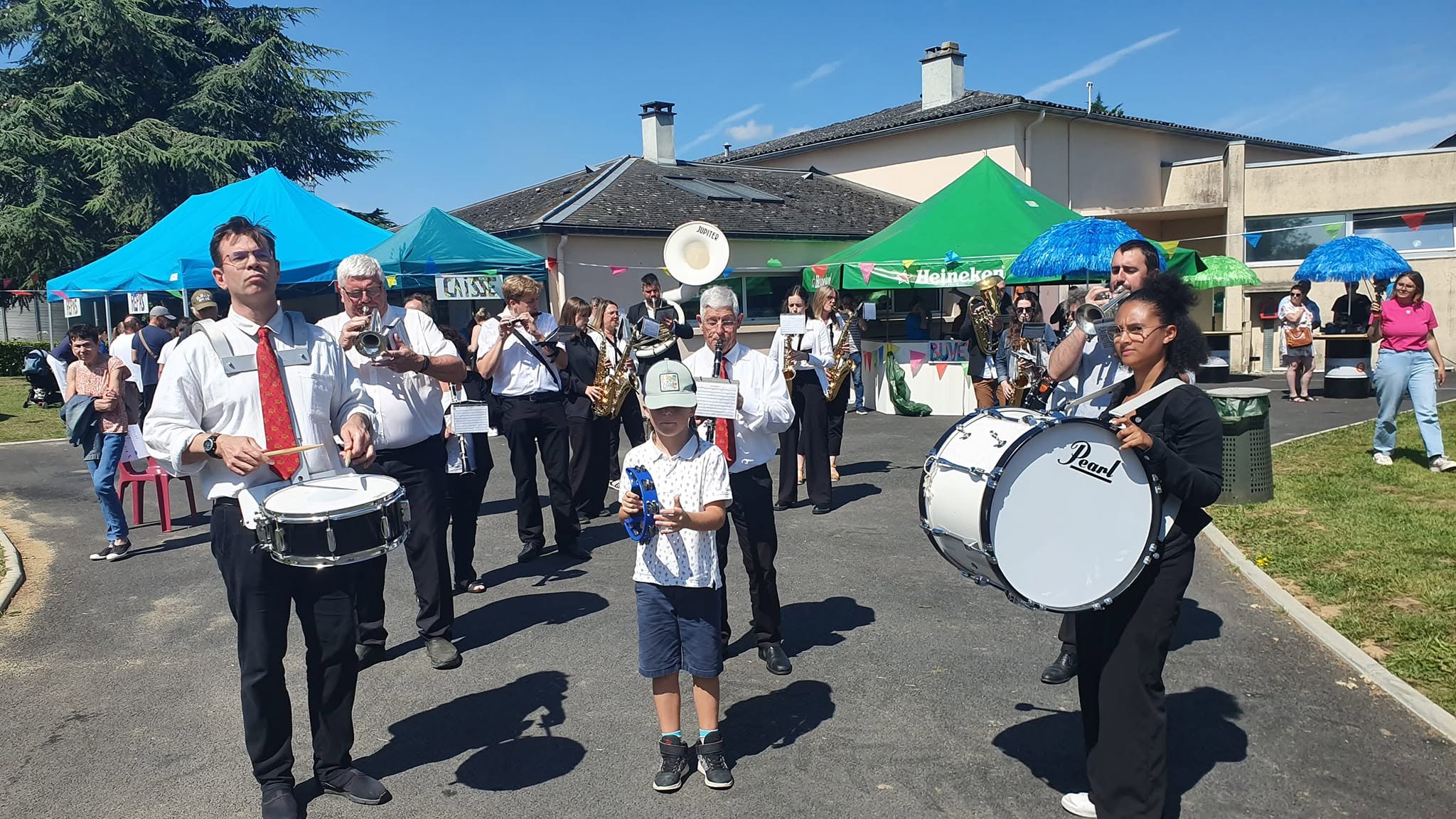 L'orchestre défilant lors d'une kermesse estivale, sous les tentes et les guirlandes